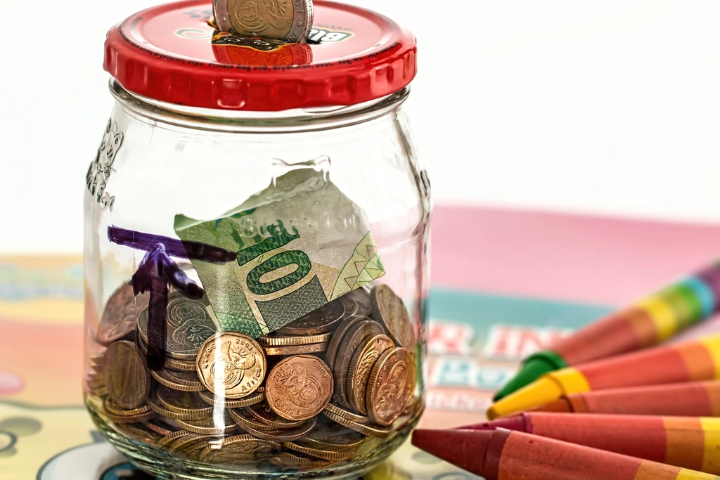 Coins in a savings jar on a desk